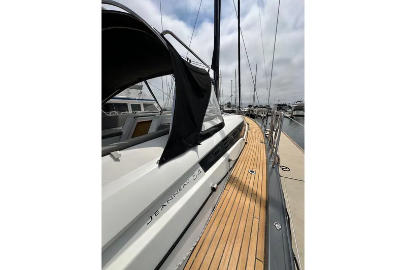 Slide: The Image of 2018 Jeanneau 54 yacht docked, showcasing sleek design and wooden deck. - 37