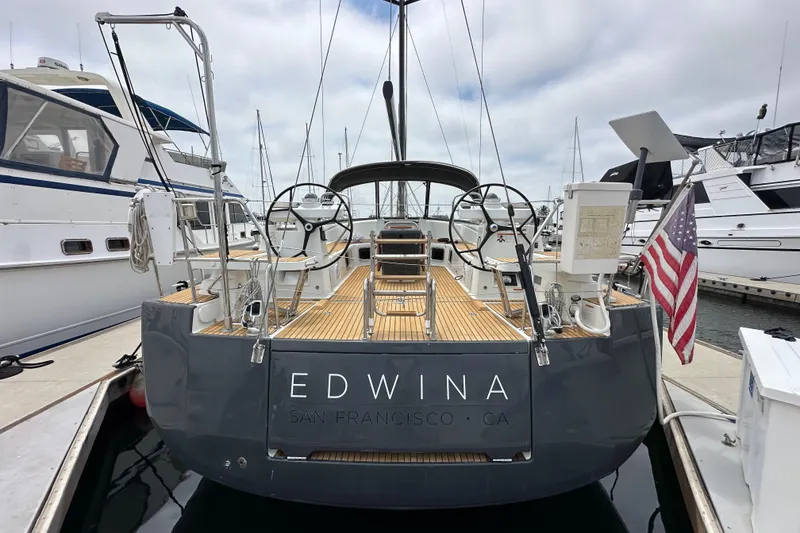 Slide: The Image of 2018 Jeanneau 54 yacht docked, rear view with dual steering wheels and American flag. - 4