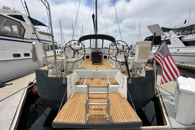 Slide: The Image of 2018 Jeanneau 54 sailboat docked, featuring dual steering wheels and American flag. - 5