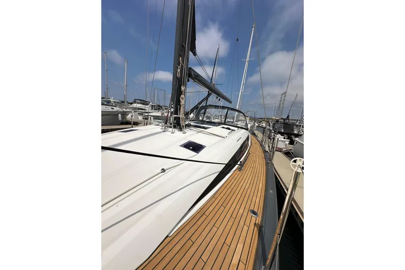 Slide: The Image of 2018 Jeanneau 54 sailboat mast against a cloudy blue sky in a marina. - 53