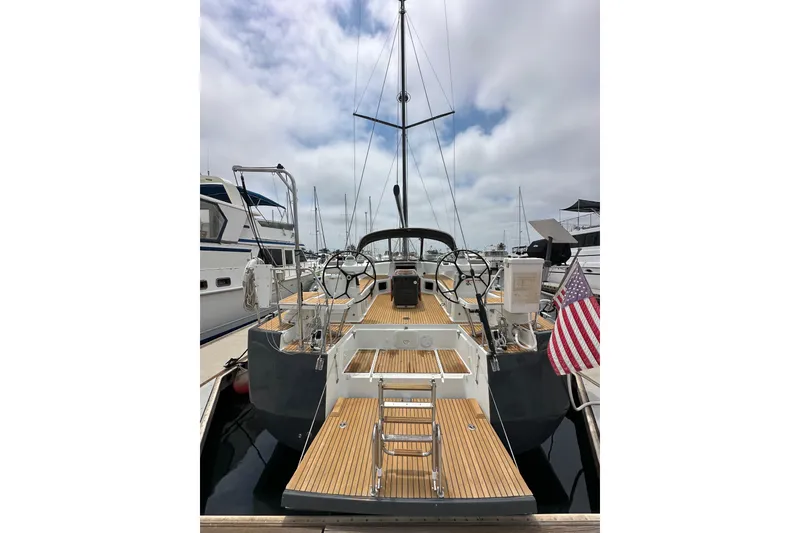 Slide: The Image of 2018 Jeanneau 54 yacht with wooden deck, docked at marina, featuring dual steering wheels. - 6