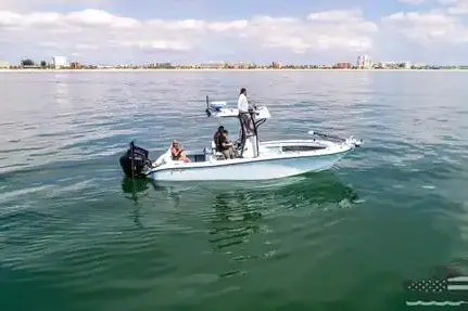 Slide: The Image of 2021 Yellowfin 26 Hybrid boat on calm water with three people onboard. - 12