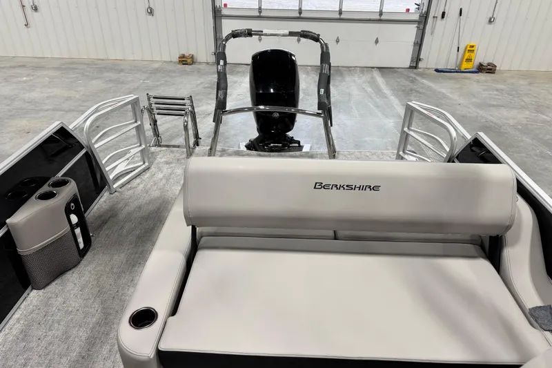 Slide: The Image of 2026 Berkshire 24 UL LE pontoon boat interior with seating and motor in a garage. - 10