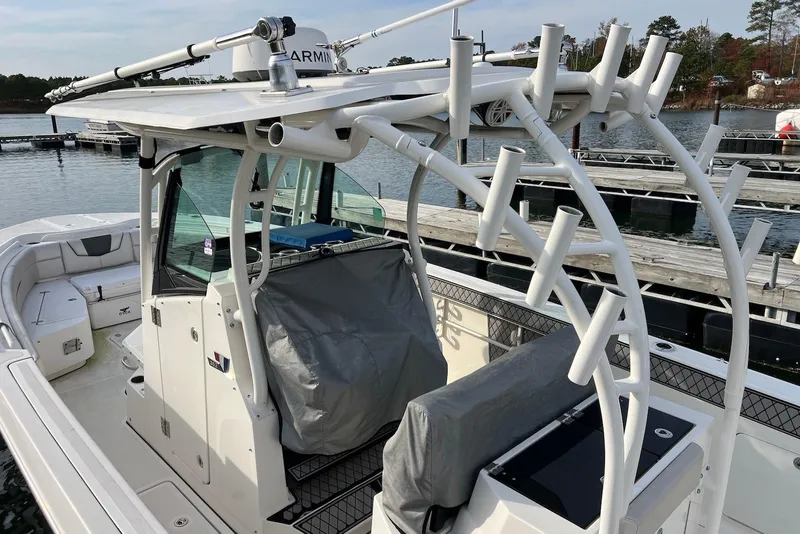Slide: The Image of 2019 Wellcraft 302 Fisherman boat docked, featuring rod holders and covered seating. - 17