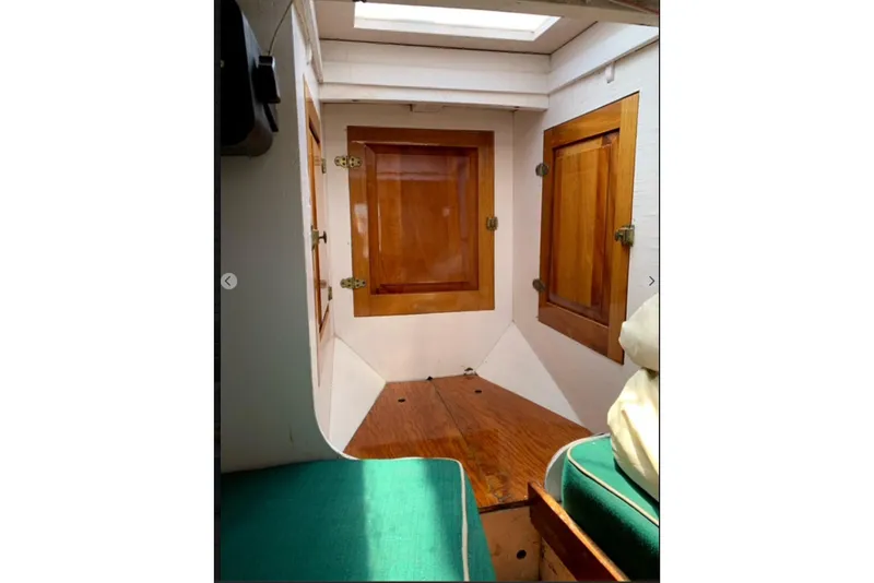Slide: The Image of Interior of 1950 Mason Ostkust Sloop with wooden cabinets and green seating. - 6