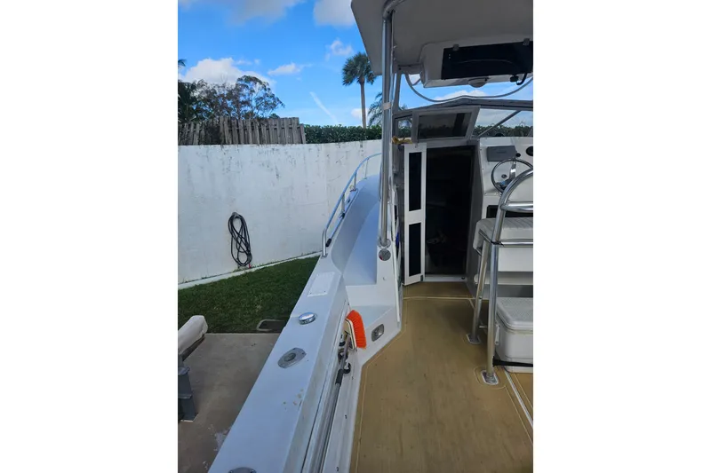 Slide: The Image of 1989 Mako 260 Walk Around boat, docked, showing deck and cabin entrance. - 2
