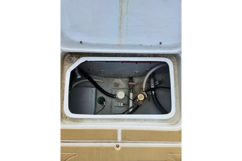 Slide: The Image of Open compartment of 1989 Mako 260 Walk Around boat showing internal components and hoses. - 9