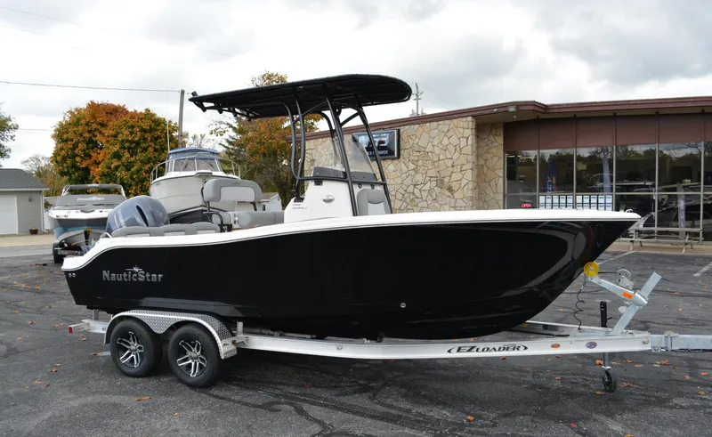 The Image of 2023 NauticStar 2102 Legacy boat on trailer, black hull, parked outdoors. - 0