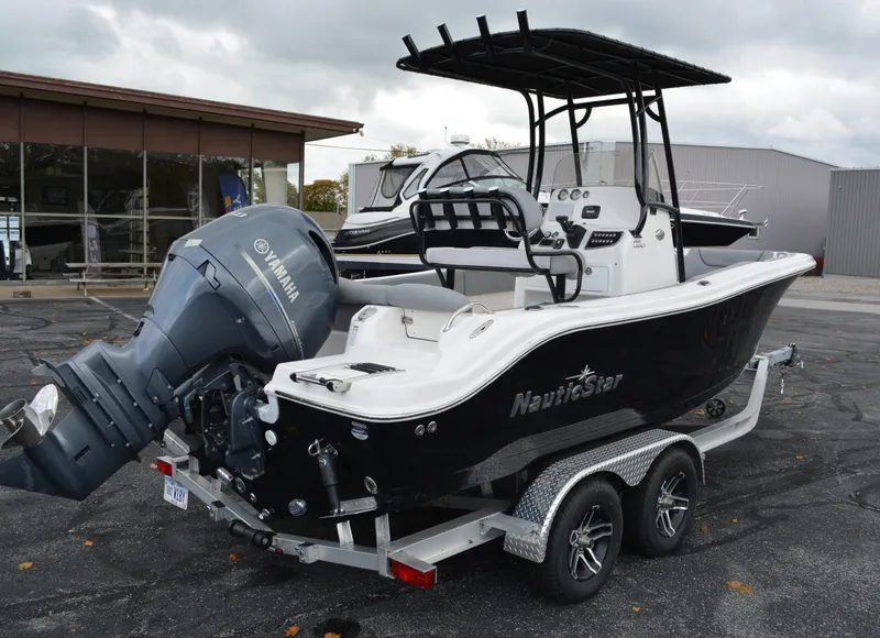 Slide: The Image of 2023 NauticStar 2102 Legacy boat on trailer with Yamaha engine, parked outdoors. - 1