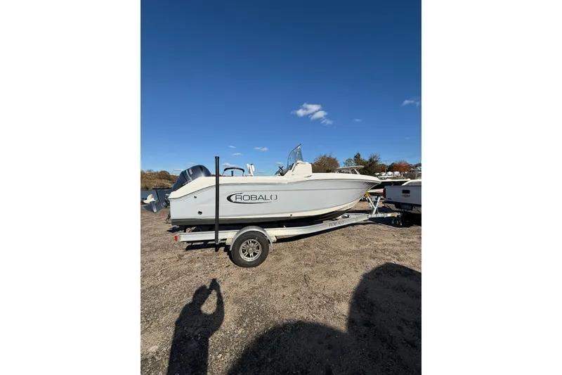 The Image of 2022 Robalo R180 Center Console boat on trailer under clear blue sky. - 0
