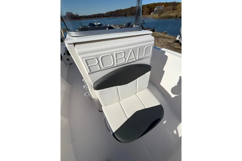 Slide: The Image of 2022 Robalo R180 Center Console boat seat with logo, docked by a scenic lake. - 8