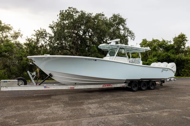 Slide: The Image of 2018 Yellowfin 39 Offshore boat on trailer, parked outdoors with trees in background. - 28
