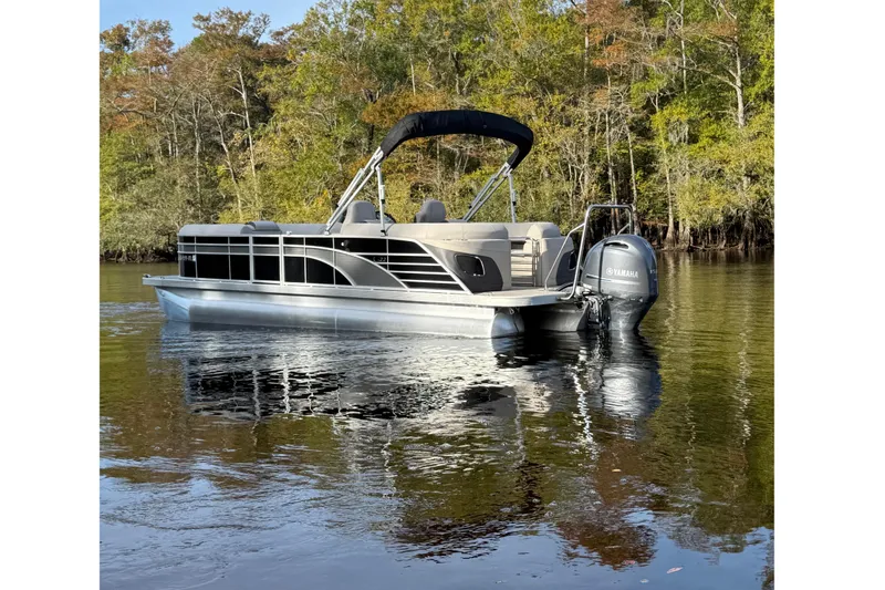 Slide: The Image of 2019 Bennington G 22 GSRFB pontoon boat on a calm lake with forest backdrop. - 2