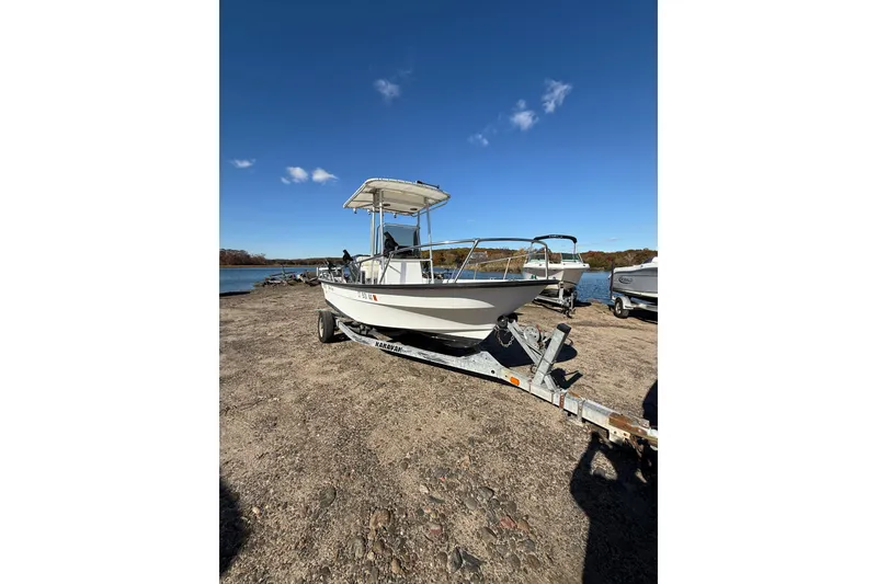 Slide: The Image of 2001 Maritime Skiff 18 on trailer by a lake under clear blue sky. - 10