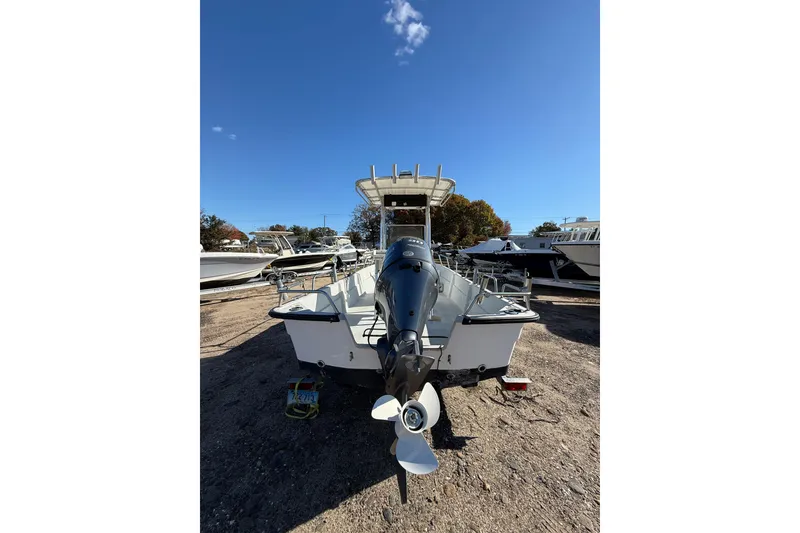 Slide: The Image of 2001 Maritime Skiff 18 boat with outboard motor, parked on gravel under clear blue sky. - 11