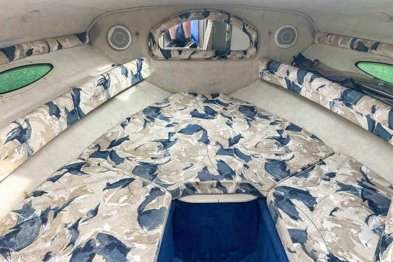 Slide: The Image of 1999 Sea Ray 215 Express Cruiser cabin interior with patterned upholstery and small windows. - 25