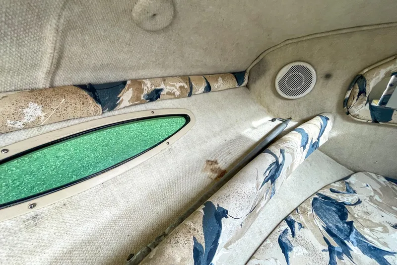 Slide: The Image of Interior of 1999 Sea Ray 215 Express Cruiser with patterned upholstery and green window. - 26