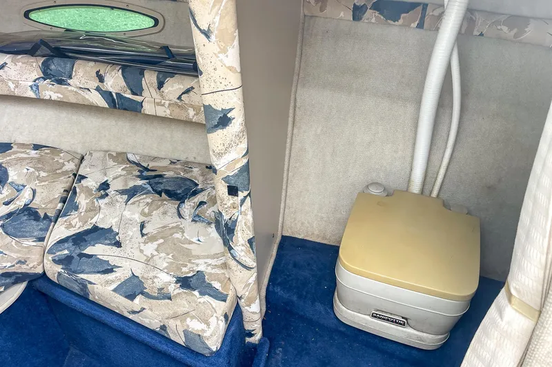 Slide: The Image of Interior of 1999 Sea Ray 215 Express Cruiser with patterned seating and portable toilet. - 27