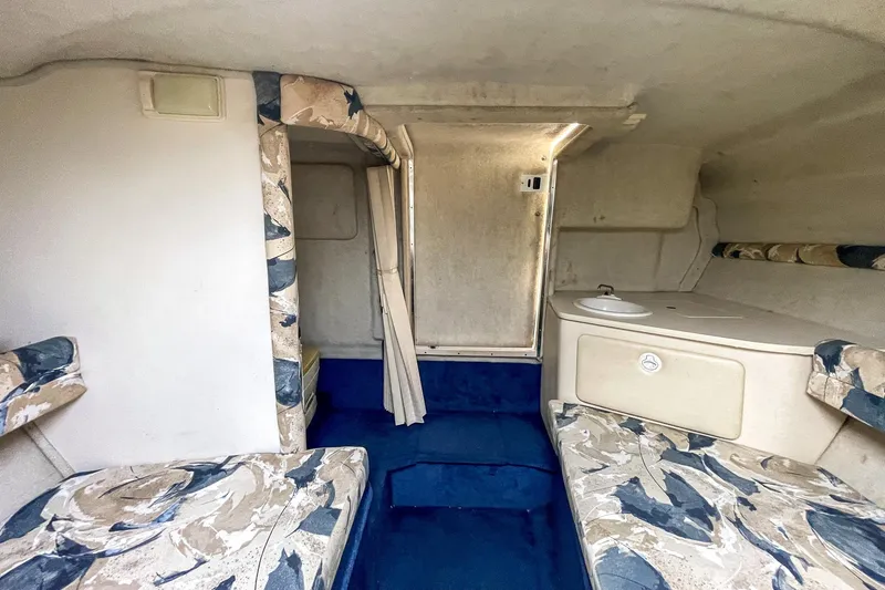 Slide: The Image of 1999 Sea Ray 215 Express Cruiser cabin interior with patterned seating and compact sink. - 28