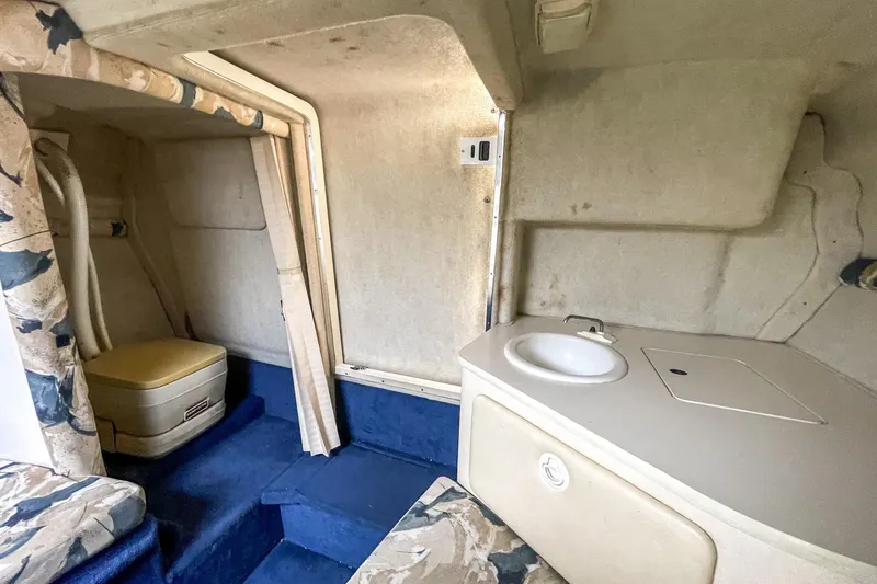 Slide: The Image of 1999 Sea Ray 215 Express Cruiser cabin interior with sink and seating area. - 29