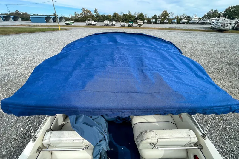 Slide: The Image of 1999 Sea Ray 215 Express Cruiser with blue canopy in a boatyard. - 31