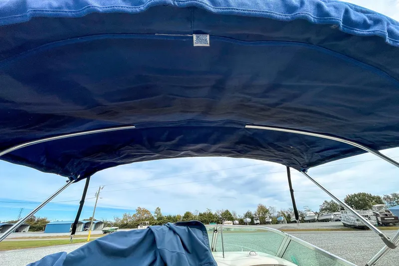 Slide: The Image of 1999 Sea Ray 215 Express Cruiser with blue bimini top, parked outdoors. - 32