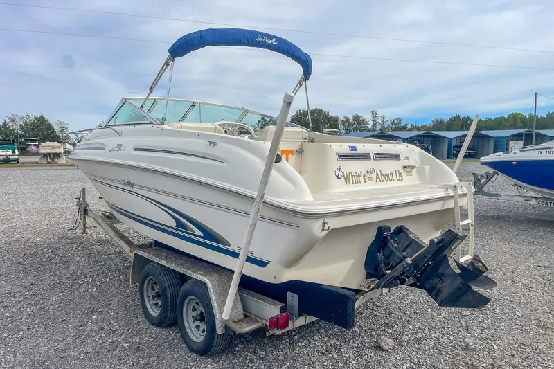 Slide: The Image of 1999 Sea Ray 215 Express Cruiser on trailer, white with blue accents, outdoor storage. - 6