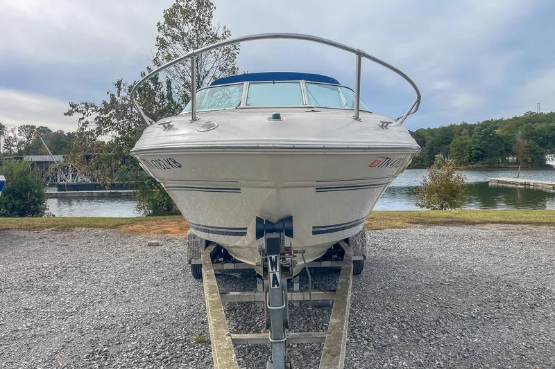 Slide: The Image of 1999 Sea Ray 215 Express Cruiser on trailer by a scenic lake. - 7