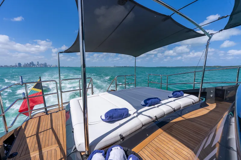 Slide: The Image of Luxurious Palmer Johnson 120 yacht deck with sunbeds, ocean view, and city skyline in the background. - 12