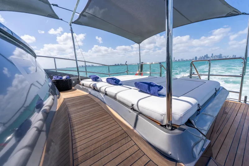 Slide: The Image of Luxurious Palmer Johnson 120 yacht deck with sun loungers, ocean view, and city skyline in background. - 49