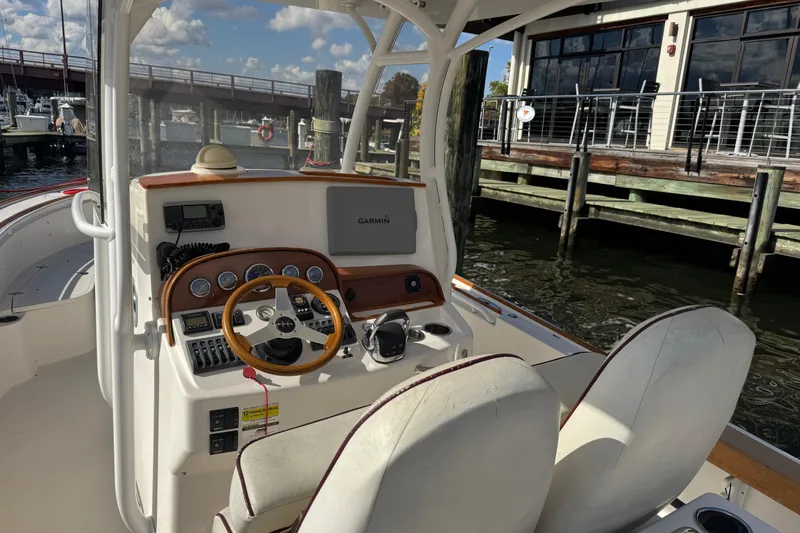 Slide: The Image of 2011 Hunt Yachts Surfhunter 25 Center Console with Garmin navigation, docked by a waterfront restaurant. - 2