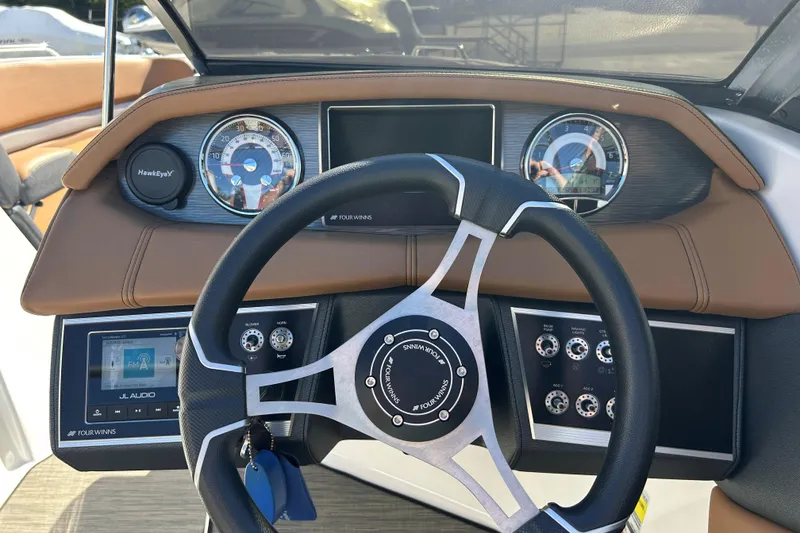 Slide: The Image of 2022 Four Winns H260 RS boat dashboard with steering wheel and control panel. - 19