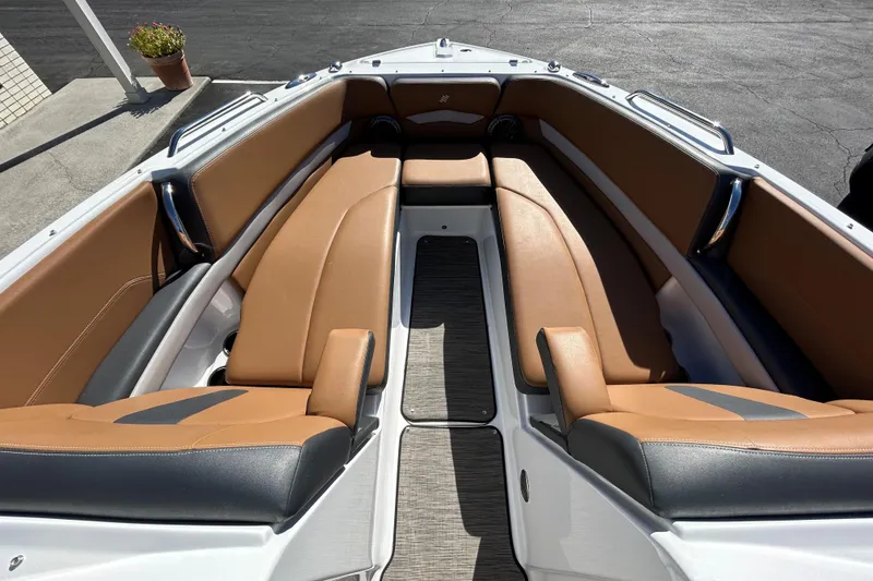 Slide: The Image of 2022 Four Winns H260 RS boat interior with tan and black seating, docked outdoors. - 21