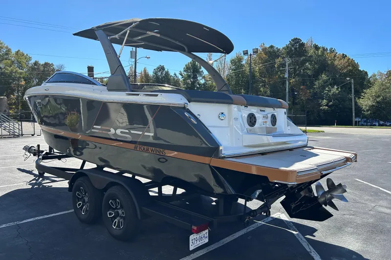 Slide: The Image of 2022 Four Winns H260 RS boat on trailer, parked outdoors under clear blue sky. - 4