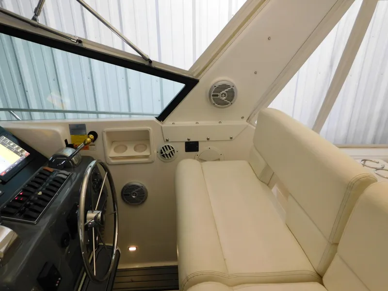 Slide: The Image of 1999 Tiara Yachts 3500 Express helm with steering wheel and white seating. - 10