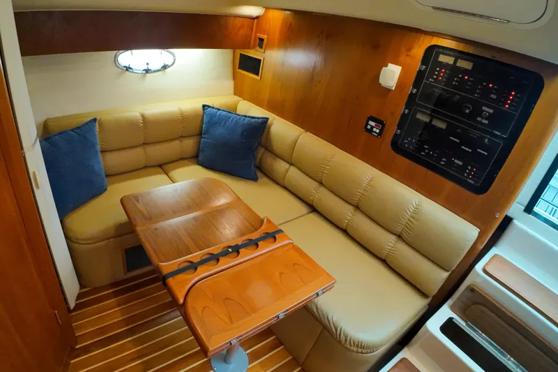 Slide: The Image of 1999 Tiara Yachts 3500 Express interior with beige seating, wooden table, and control panel. - 101