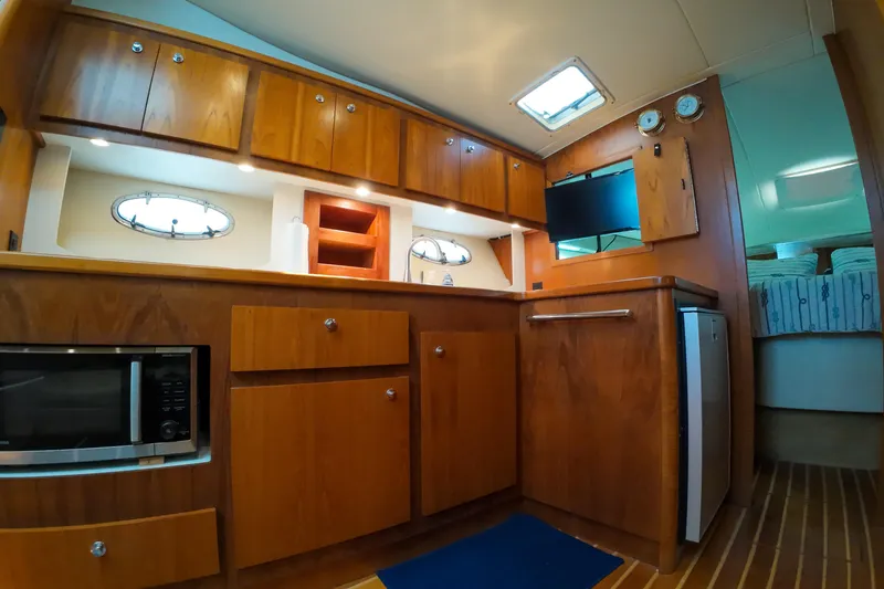 Slide: The Image of 1999 Tiara Yachts 3500 Express interior with wooden cabinetry, microwave, and compact fridge. - 118