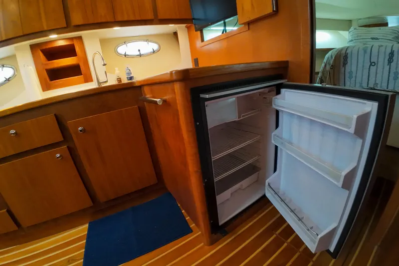 Slide: The Image of 1999 Tiara Yachts 3500 Express interior with open fridge and wooden cabinetry. - 119