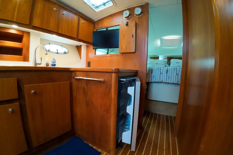 Slide: The Image of 1999 Tiara Yachts 3500 Express interior with wood cabinetry and compact kitchen area. - 120