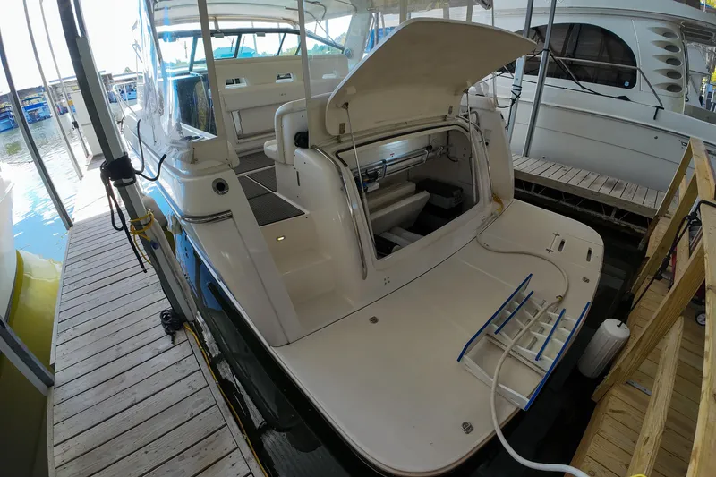 Slide: The Image of 1999 Tiara Yachts 3500 Express docked, showcasing open storage compartment and spacious deck. - 126