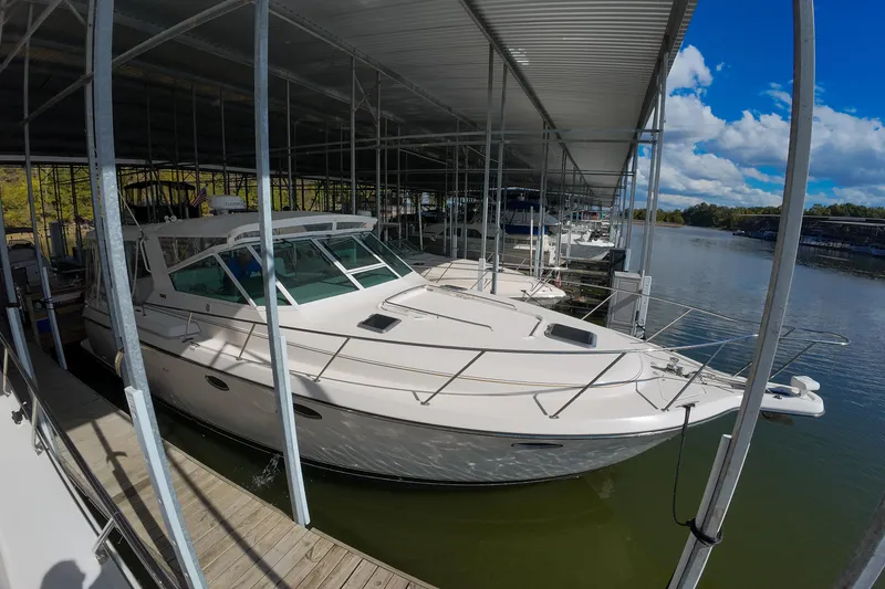 Slide: The Image of 1999 Tiara Yachts 3500 Express docked under a covered marina on a sunny day. - 127
