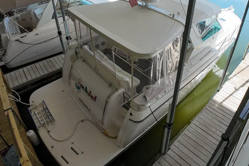 Slide: The Image of 1999 Tiara Yachts 3500 Express docked, featuring a spacious deck and covered seating area. - 128