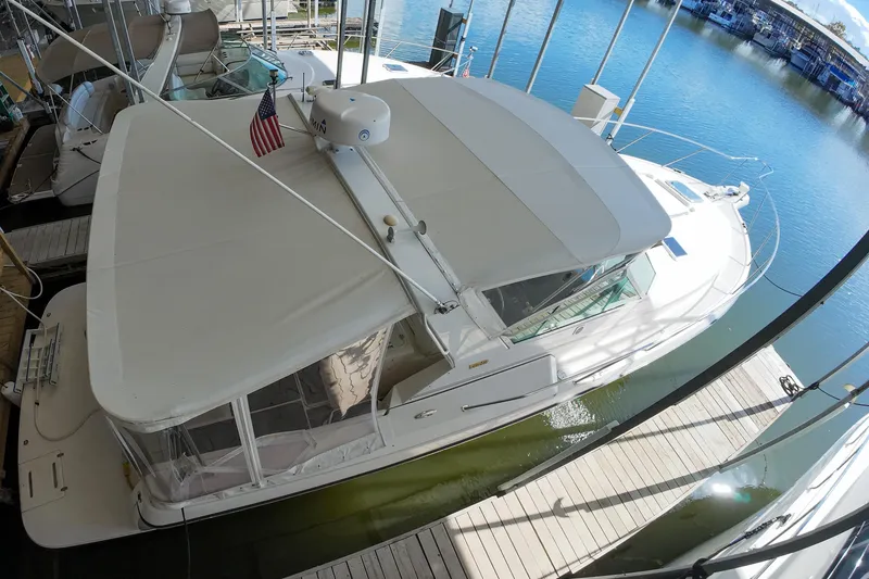 Slide: The Image of 1999 Tiara Yachts 3500 Express docked, featuring a spacious deck and canopy. - 130