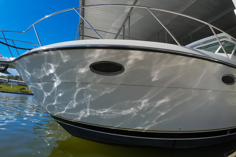 Slide: The Image of 1999 Tiara Yachts 3500 Express reflecting sunlight on water under a dock. - 138