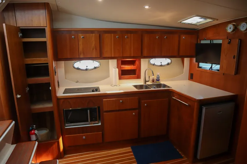 Slide: The Image of Interior of 1999 Tiara Yachts 3500 Express, featuring a well-equipped kitchen with wooden cabinetry. - 155