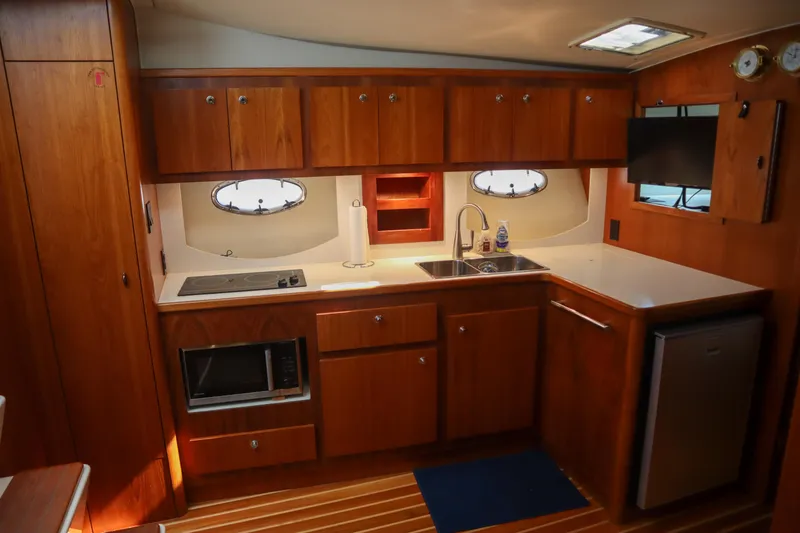Slide: The Image of 1999 Tiara Yachts 3500 Express kitchen with wood cabinetry, sink, stove, and microwave. - 161