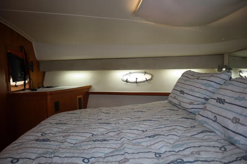 Slide: The Image of 1999 Tiara Yachts 3500 Express cabin interior with bed, porthole, and TV. - 165