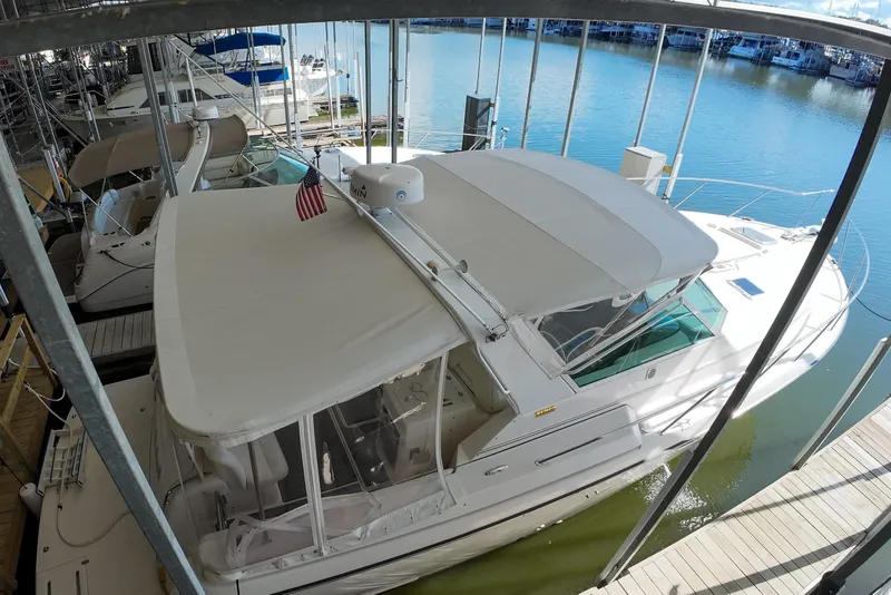 Slide: The Image of 1999 Tiara Yachts 3500 Express docked in a marina, covered with a canopy. - 2