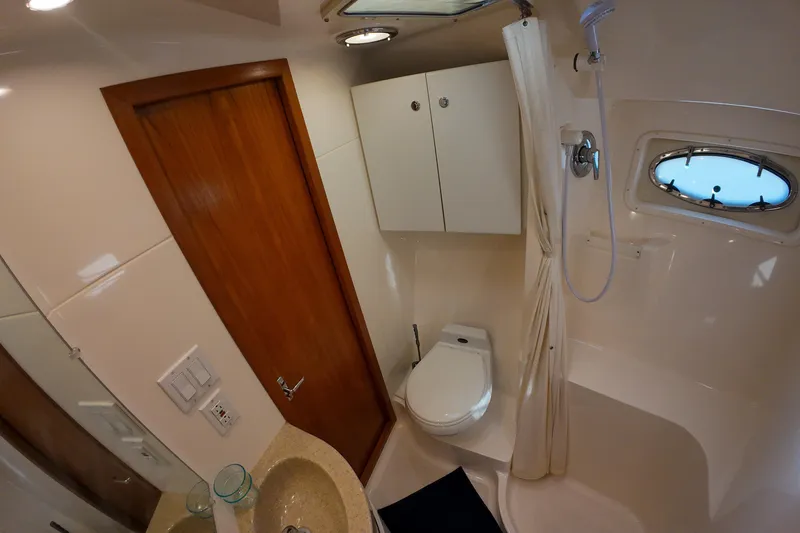 Slide: The Image of 1999 Tiara Yachts 3500 Express bathroom with shower, sink, and wooden door. - 220