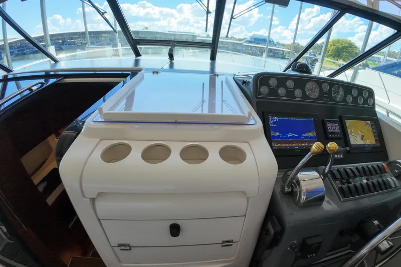 Slide: The Image of 1999 Tiara Yachts 3500 Express helm with navigation screens and controls, docked under a sunny sky. - 225